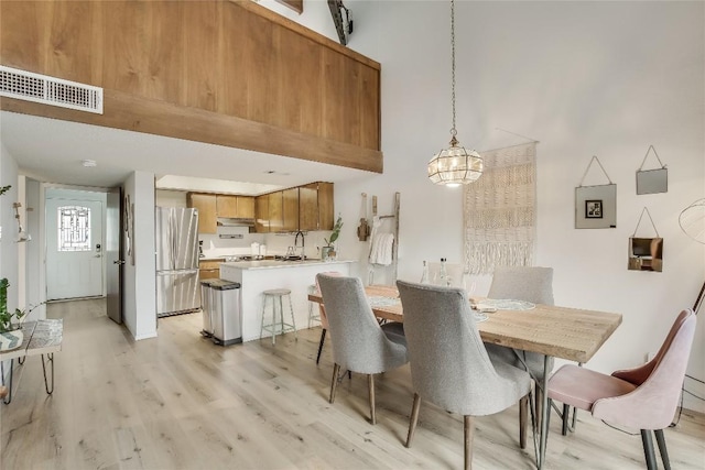 dining room with a high ceiling and light wood-type flooring