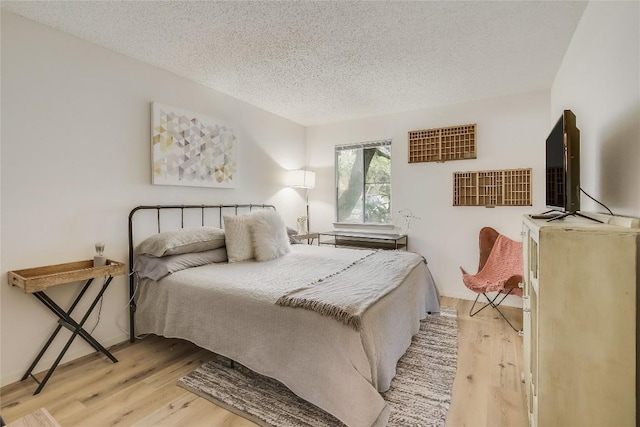 bedroom featuring light hardwood / wood-style floors and a textured ceiling