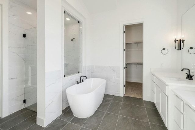 bathroom featuring vanity, independent shower and bath, tile walls, and tile patterned flooring