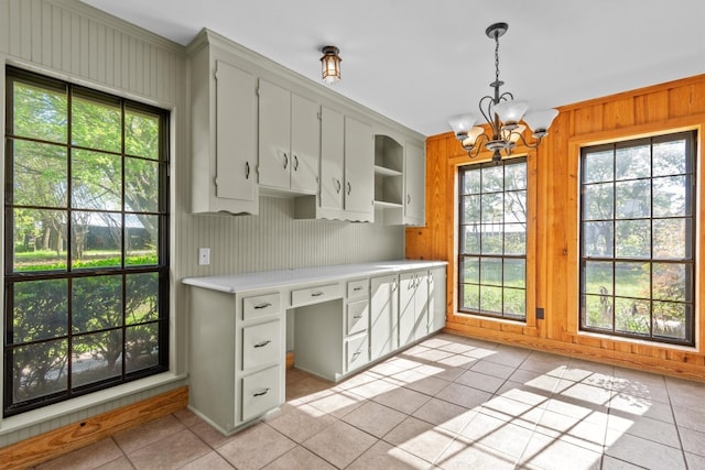 kitchen with light tile patterned flooring, wooden walls, hanging light fixtures, and a wealth of natural light