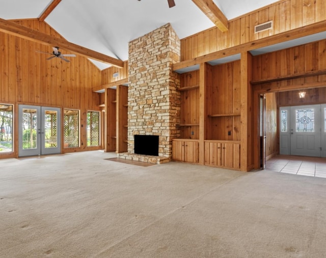 unfurnished living room with high vaulted ceiling, beam ceiling, ceiling fan, and a stone fireplace