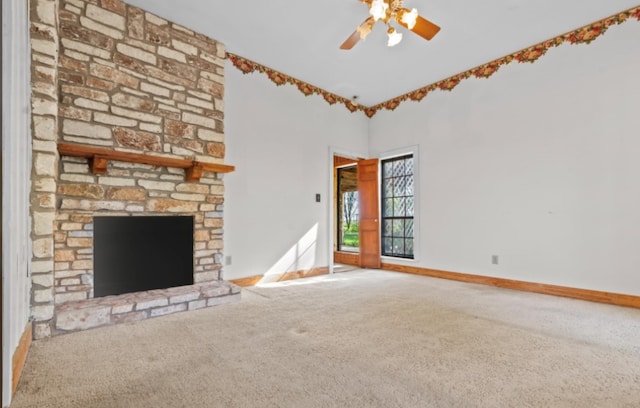 unfurnished living room featuring ceiling fan, a stone fireplace, and carpet flooring