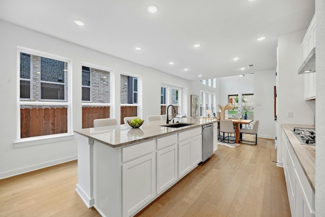 kitchen featuring white cabinets, light hardwood / wood-style flooring, a center island with sink, and sink