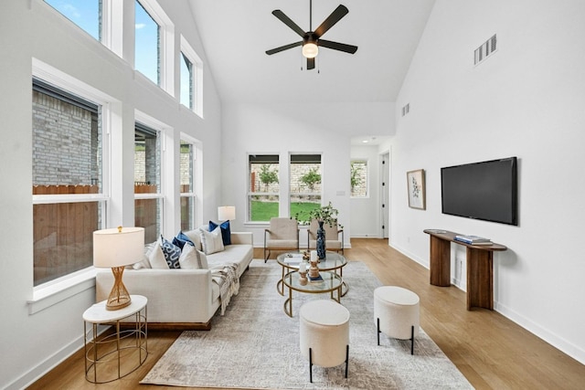 living room featuring high vaulted ceiling, ceiling fan, and light hardwood / wood-style flooring