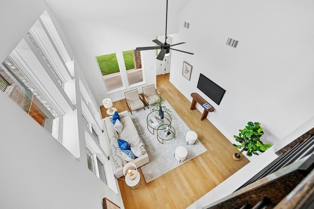 living room with a high ceiling, hardwood / wood-style floors, and ceiling fan