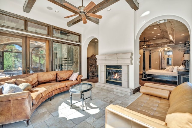 living room with a fireplace, a high ceiling, and ceiling fan