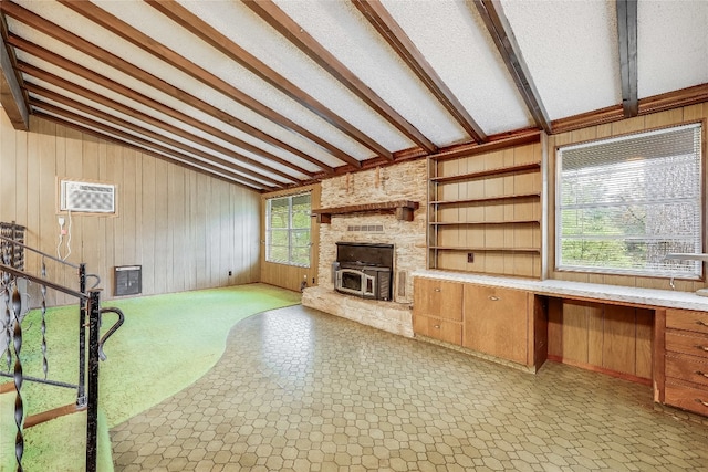 unfurnished living room with vaulted ceiling with beams, wooden walls, a fireplace, built in desk, and light tile patterned flooring