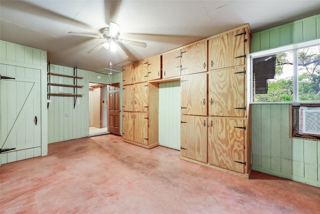 interior space with wood walls and ceiling fan