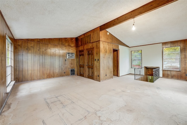 interior space with vaulted ceiling with beams, wooden walls, and a textured ceiling