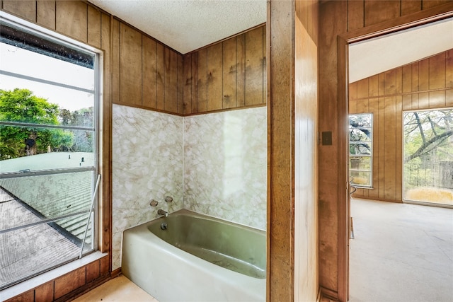 bathroom featuring wood walls, a textured ceiling, and vaulted ceiling