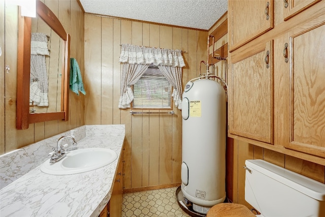 bathroom featuring water heater, wooden walls, a textured ceiling, toilet, and vanity