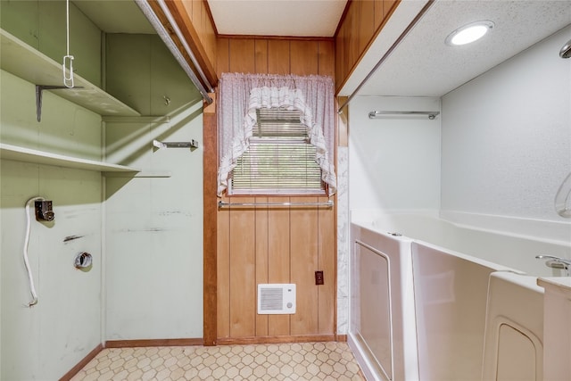 washroom featuring light tile patterned flooring, a textured ceiling, and wooden walls