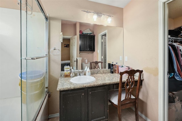 bathroom with tile floors, vanity, and enclosed tub / shower combo