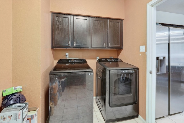 washroom featuring washing machine and clothes dryer, cabinets, and light tile flooring