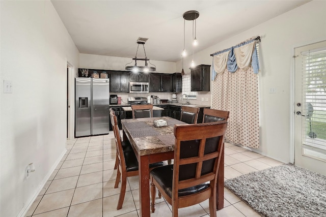 dining area with an inviting chandelier, sink, and light tile floors