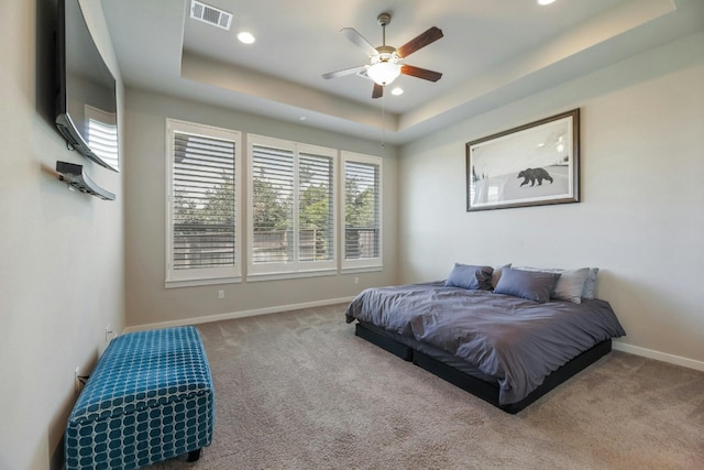 carpeted bedroom featuring a tray ceiling and ceiling fan