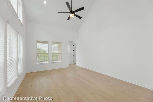 empty room with light hardwood / wood-style floors, ceiling fan, and high vaulted ceiling