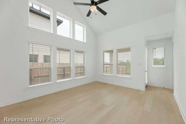 empty room with high vaulted ceiling, ceiling fan, and light wood-type flooring