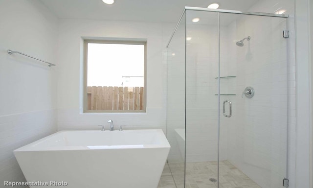 bathroom with tile walls and shower with separate bathtub