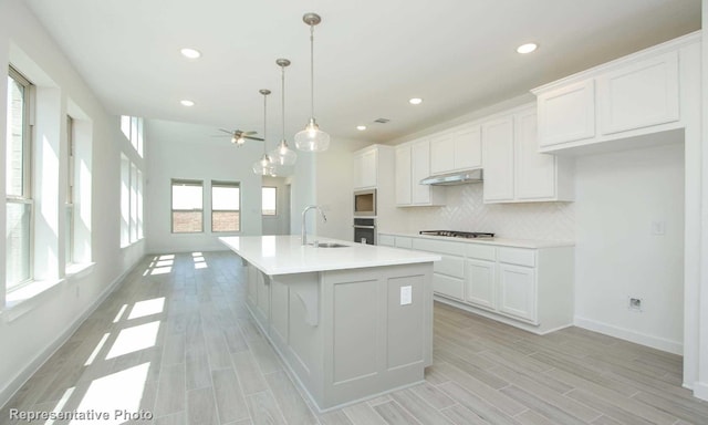 kitchen with sink, an island with sink, white cabinetry, and stainless steel appliances