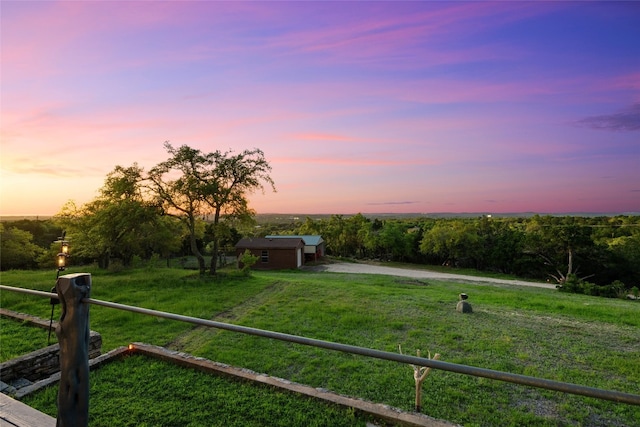 yard at dusk featuring a rural view