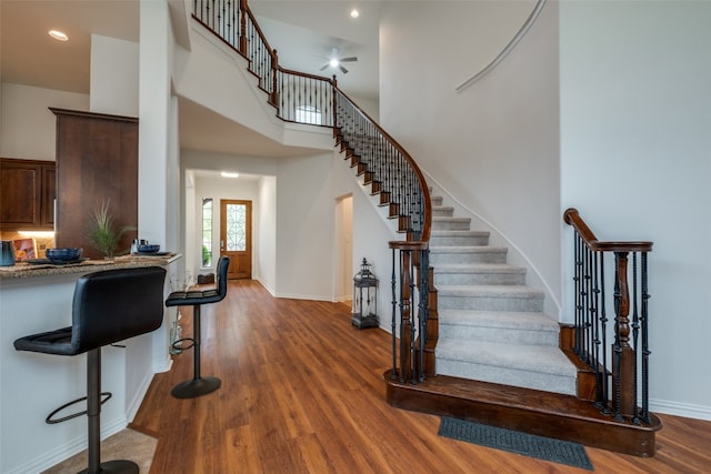 interior space with a high ceiling, ceiling fan, and dark hardwood / wood-style flooring