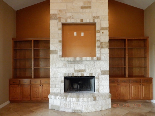 unfurnished living room with lofted ceiling, light tile floors, and a stone fireplace