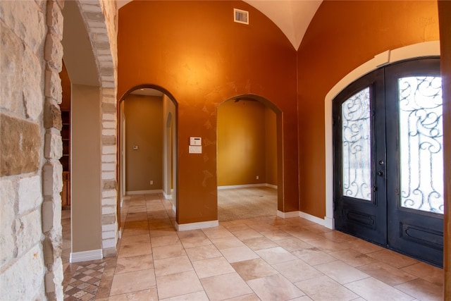 tiled foyer featuring high vaulted ceiling and french doors