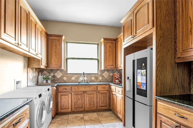 kitchen featuring backsplash, stainless steel refrigerator, light tile floors, and washing machine and clothes dryer