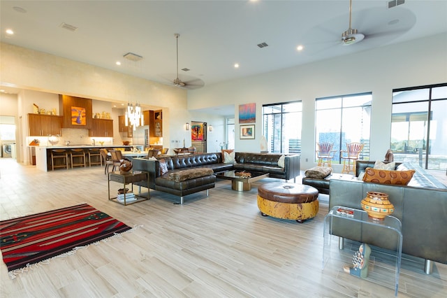 living room with ceiling fan with notable chandelier and light hardwood / wood-style flooring