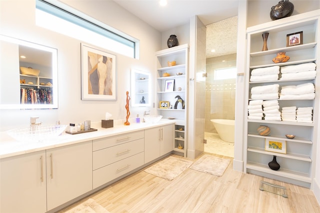 bathroom featuring hardwood / wood-style flooring, vanity, and a tile shower