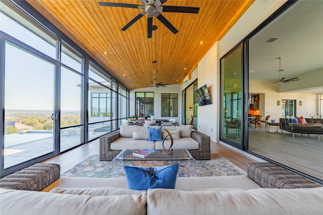 sunroom / solarium with lofted ceiling, wooden ceiling, and ceiling fan