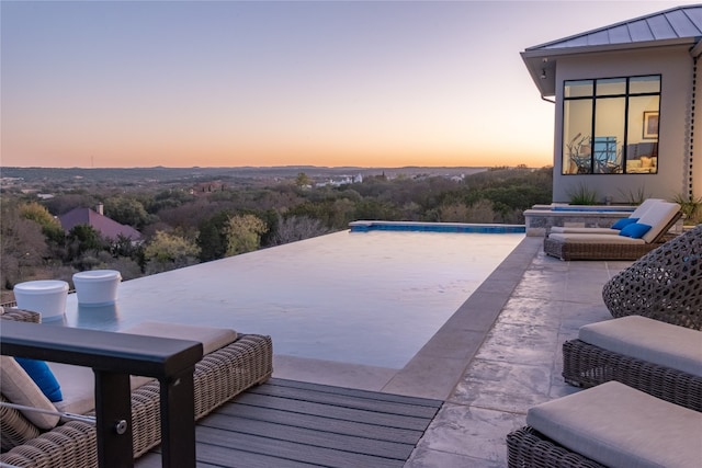 pool at dusk featuring a patio area