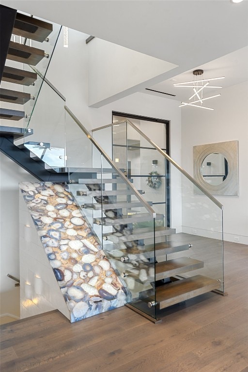 stairs with an inviting chandelier and hardwood / wood-style floors