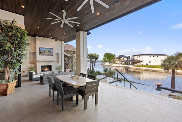 view of patio featuring exterior fireplace, a water view, and ceiling fan