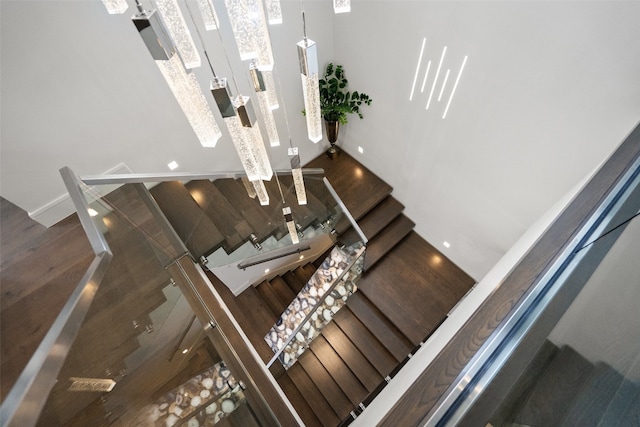 stairs with dark hardwood / wood-style floors and a towering ceiling