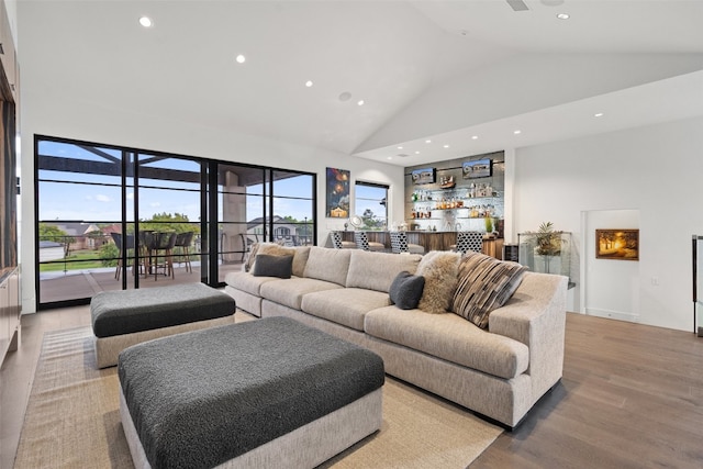 living room with high vaulted ceiling, light hardwood / wood-style floors, and a healthy amount of sunlight