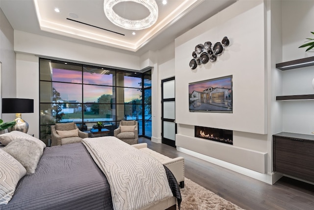 bedroom featuring dark hardwood / wood-style floors, access to outside, and a raised ceiling