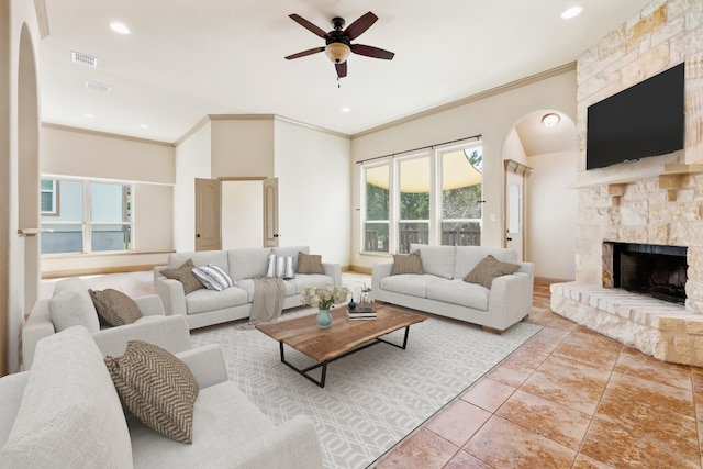 tiled living room featuring ceiling fan, a fireplace, plenty of natural light, and ornamental molding