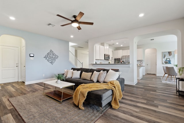 living room with ceiling fan and dark wood-type flooring