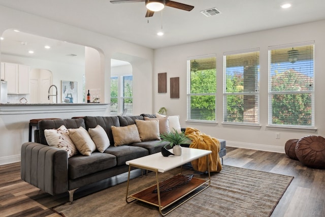 living room featuring ceiling fan and dark wood-type flooring