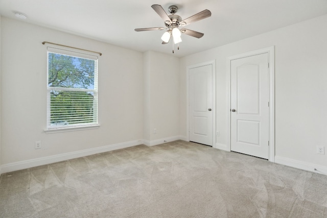 unfurnished bedroom featuring light carpet, two closets, and ceiling fan