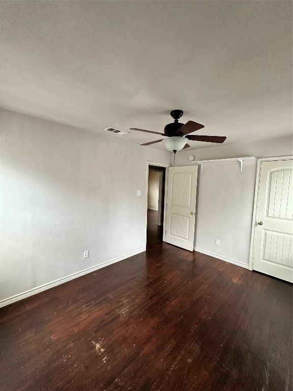 spare room featuring ceiling fan and dark wood-type flooring