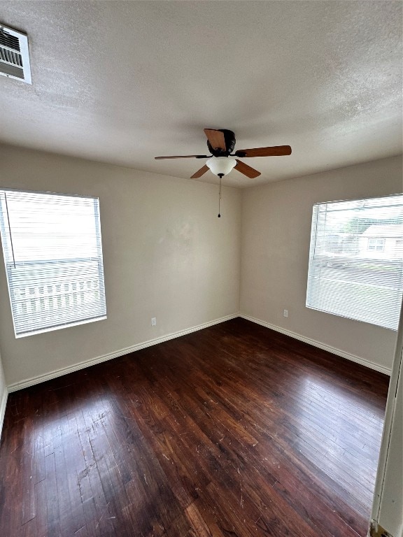 empty room featuring ceiling fan, a textured ceiling, and dark wood-type flooring