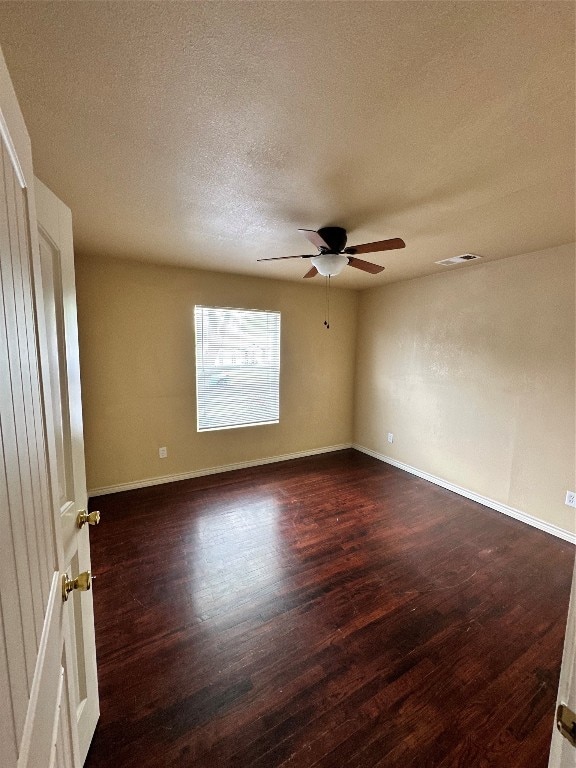 spare room with ceiling fan, dark wood-type flooring, and a textured ceiling