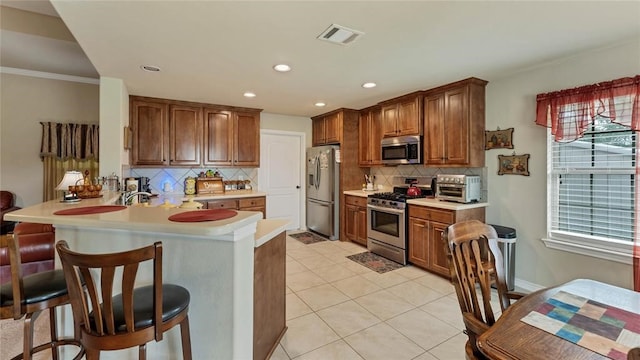 188 Zindler Ln, Paige, TX 78659 - kitchen featuring a breakfast bar, appliances with stainless steel finishes, tasteful backsplash, light tile floors, and kitchen peninsula