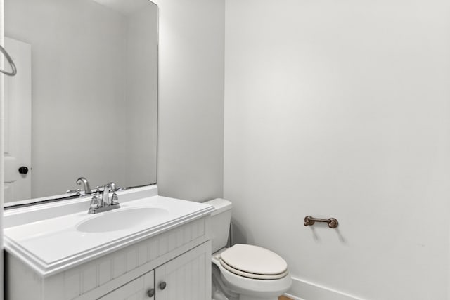 bathroom featuring baseboards, vanity, and toilet