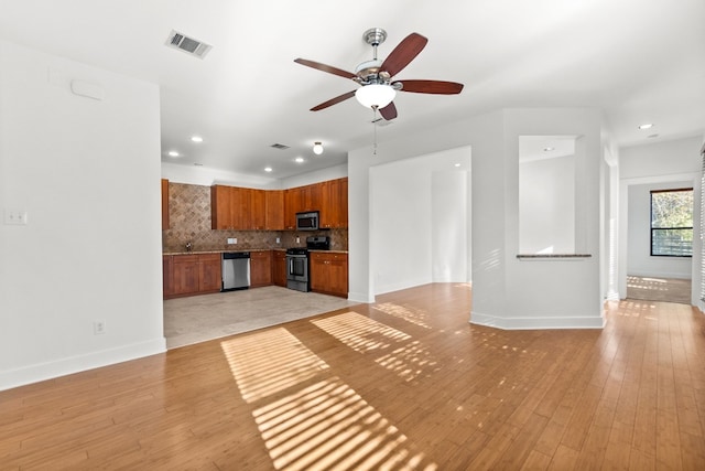 unfurnished living room featuring light wood-type flooring, baseboards, visible vents, and a ceiling fan