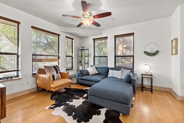 living room featuring light wood finished floors, baseboards, and a ceiling fan