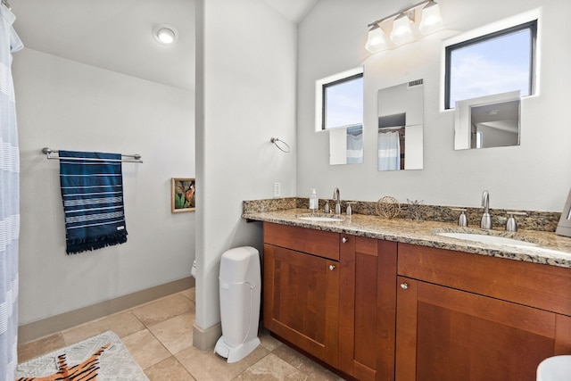 full bath with double vanity, tile patterned flooring, a sink, and toilet